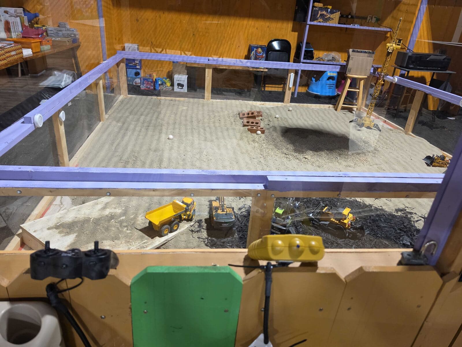 Sand digging area with toy dump trucks, excavators and a crane