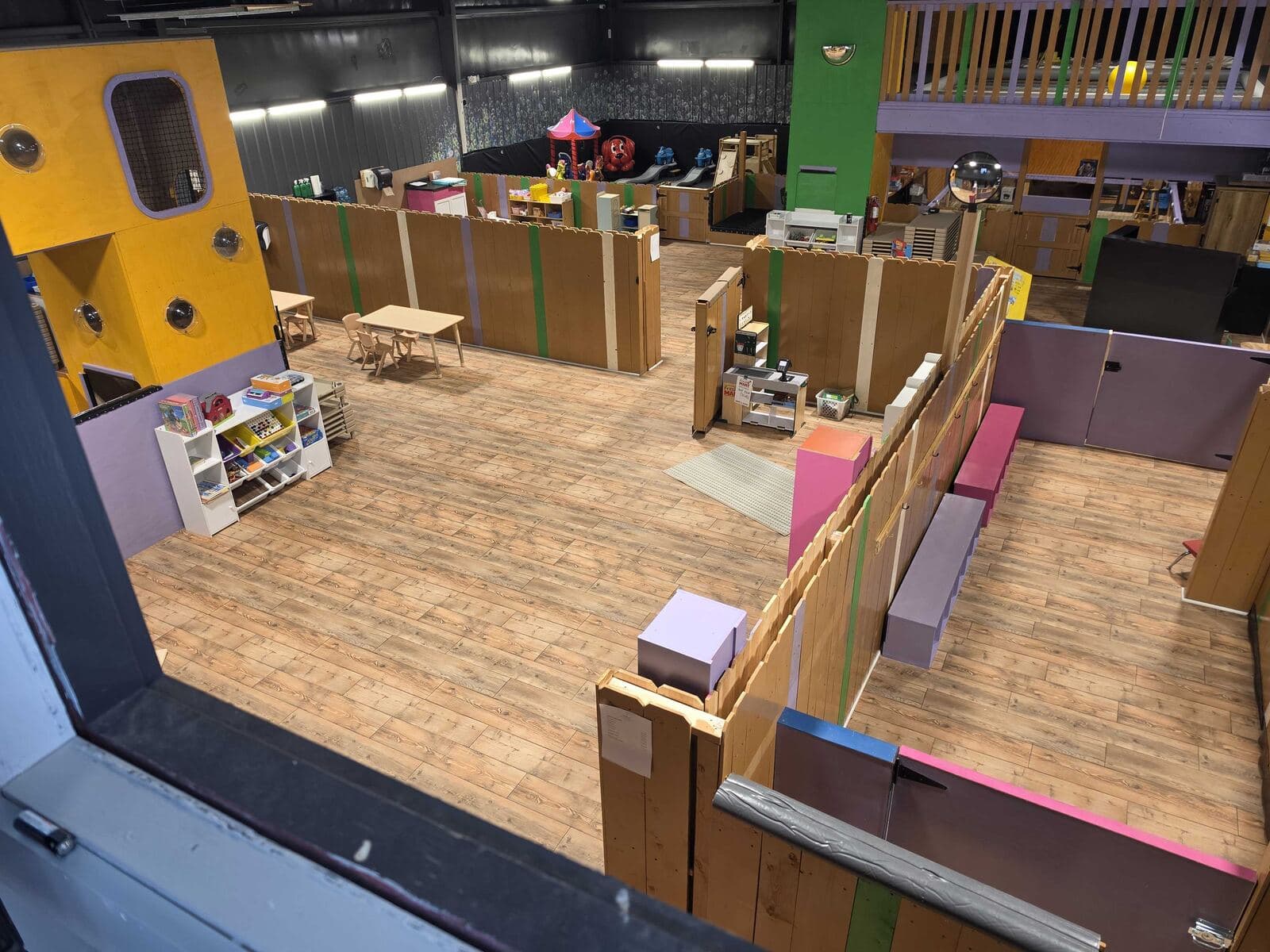 Overhead view of the Sprouting Spot play floor with a yellow playhouse, fenced play zones and child-size tables