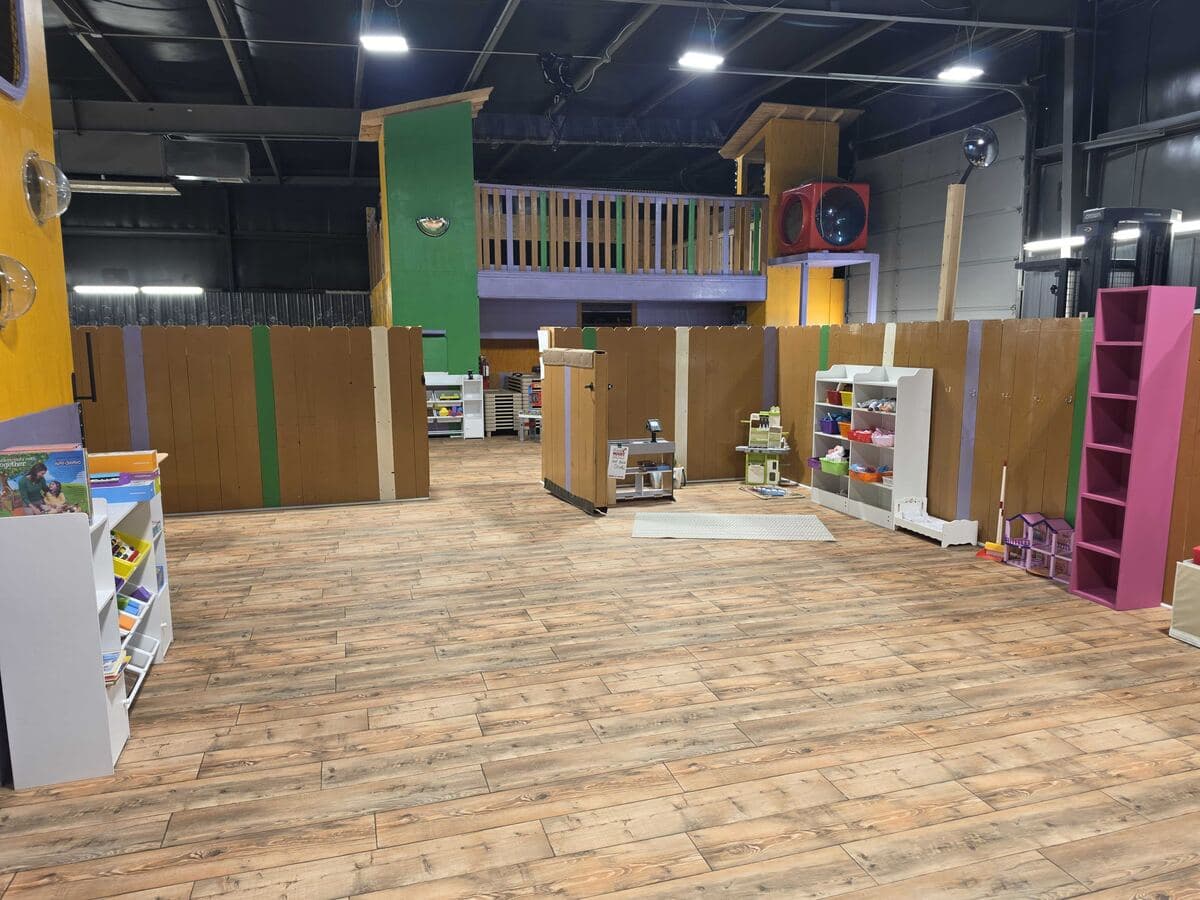Pretend-play market stand and colorful shelving on the play floor